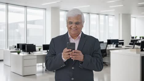 Happy-Indian-senior-manager-using-mobile-phone