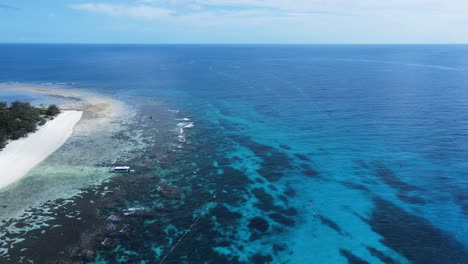 vue en hauteur sur un système de récifs sous-marins vers un groupe de bateaux amarrés dans les eaux tropicales bleues de l'île