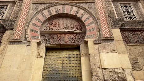 north gate of córdoba’s mezquita-catedral, featuring detailed stonework, horseshoe arch, and islamic geometric patterns from andalusian heritage.