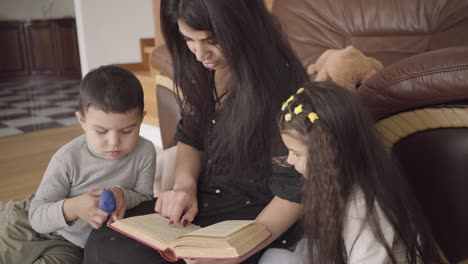 charming middle eastern woman reading the book to little children