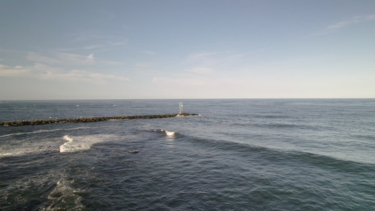 빠른 해변 드론 공중  ⁇ 은 부두와 등대 타워 표시 보트 채널을 향해 바위를 따라 이동