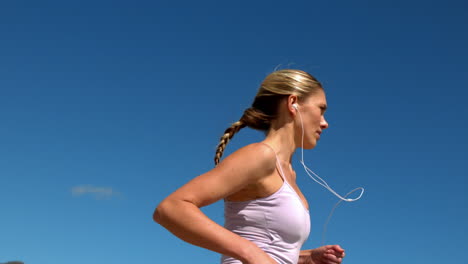 Fit-blonde-jogging-and-listening-to-music-on-sunny-day