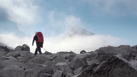 Spectacular-shot-of-person-hiking-with-mountain-peak-in-background-arising-above-the-clouds-and-fog-during-fall