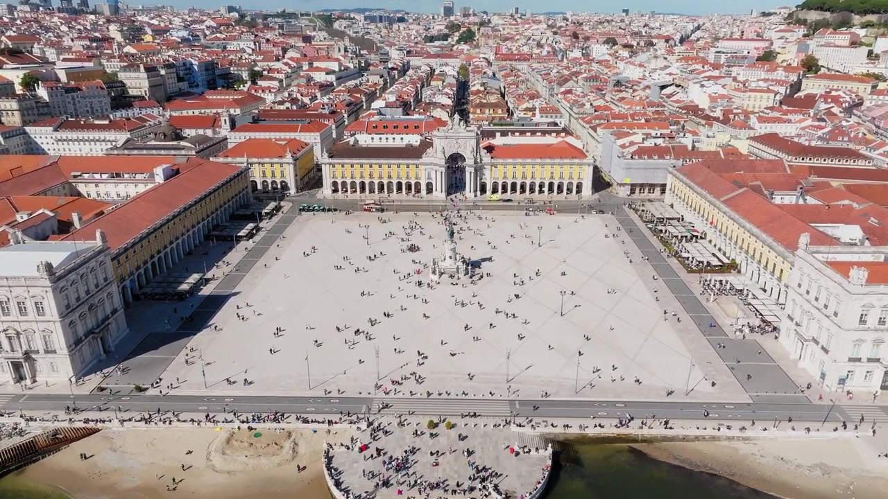 Ripresa panoramica con drone di Praça do Comércio e Arco della Rua Augusta, Lisbona a mezzogiorno. Folla vivace, giornata di sole splendente, cielo azzurro limpido. Portogallo.