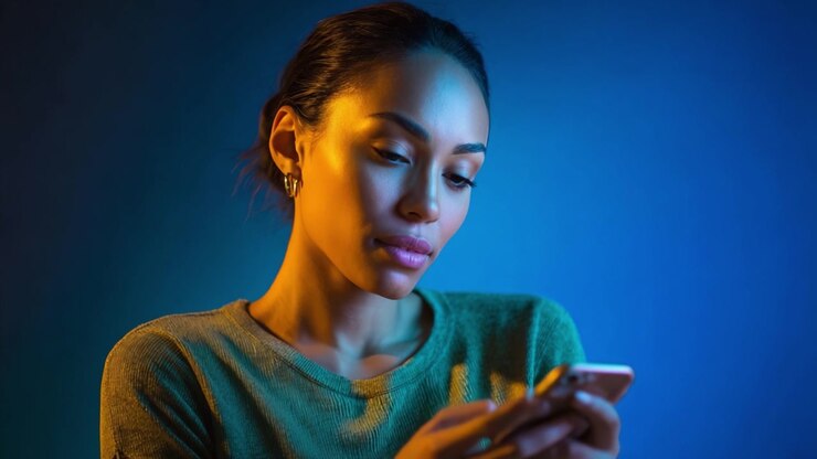 A Thoughtful Woman Engaged with Her Smartphone in an Artistically Lit Environment, Capturing a Moment of Reflection and Connection in Modern Technology