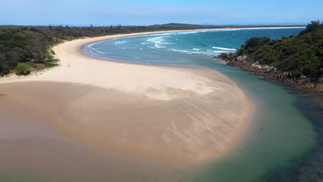 Filmische,-Hochkippende-Drohnenaufnahme-Des-Südpazifik-Und-Des-Korogoro-Creek-Mit-Wind,-Der-Sand-über-Eine-Sandbank-Am-Hutkopf,-New-South-Wales,-Australien,-Bläst