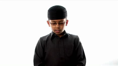 a young boy prays while wearing a tight fitting hat