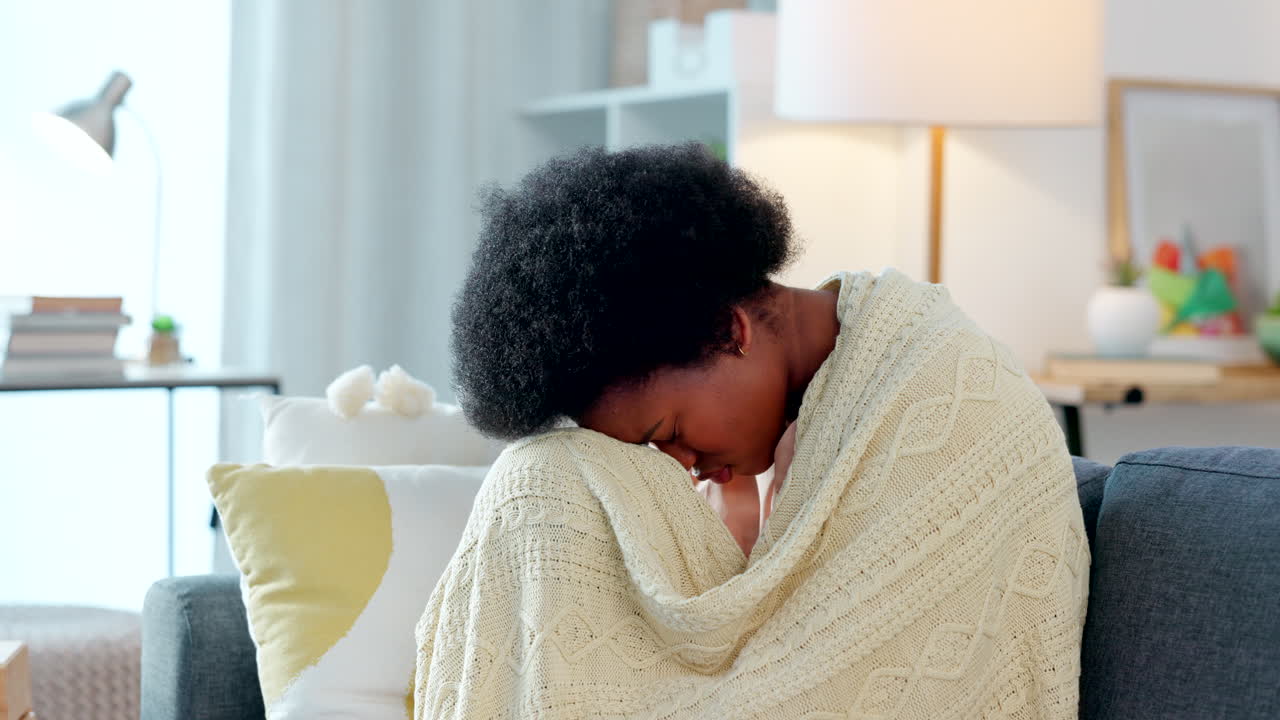 Donna seduta su un divano coperta da una coperta