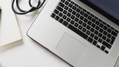 video of laptop, stethoscope, pen, notebook and smartphone on white background