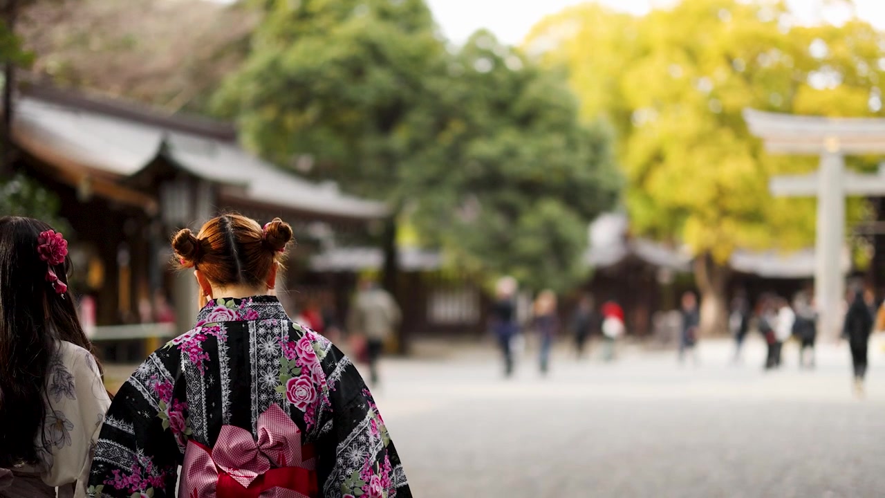 Vista di spalle di una donna in yukata tradizionale che cammina attraverso l'area del santuario Meiji Jingu a Tokyo.
