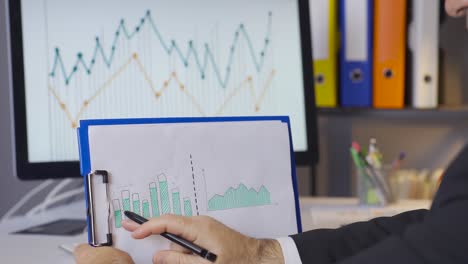 close-up of businessman analyzing financial charts in company.