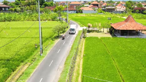 在晴朗的晴天,在canggu bali的摩托车上旅行的夫妇的空中景色