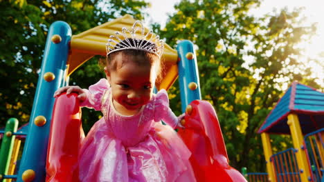 toddler princess playing on a playground slide