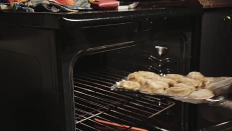 Man-Placing-The-Breaded-Meat-Inside-The-Pre-Heated-Oven-For-Baking---Close-Up-Shot