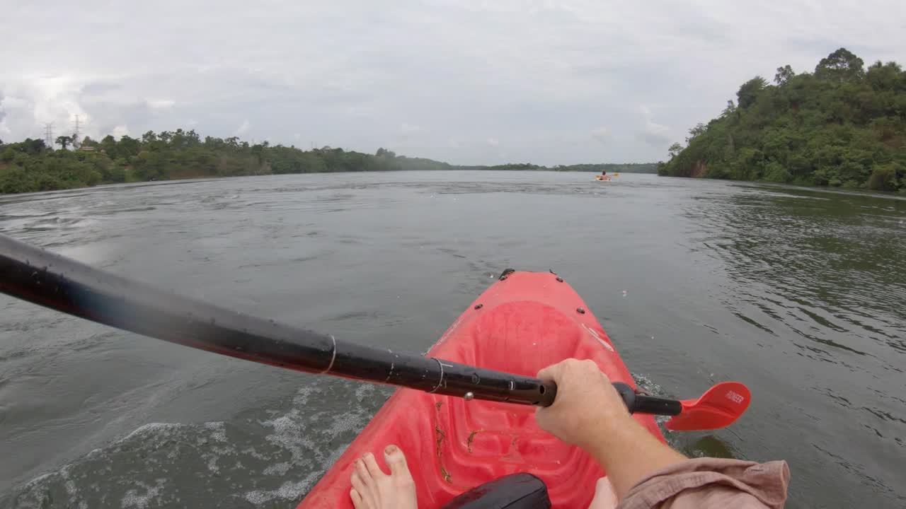 un punto de vista de un hombre en un kayak rojo remando por el río nilo