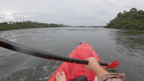 a point of view shot of a man on a red kayak paddling down the nile river