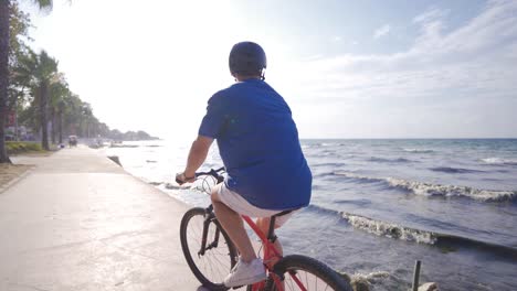 joven montando una bicicleta en la playa.