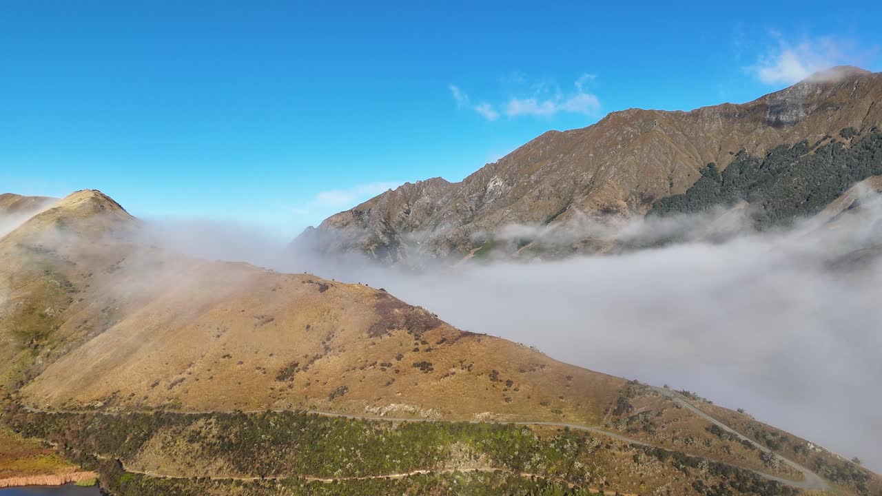Aerial view of Queenstown's mist-covered mountains during sunrise, showcasing clear skies and serene landscapes