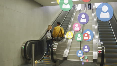 animation of social media icons floating over happy caucasian couple holding hands on escalators