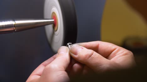 Hands-of-male-jewelry-maker-hand-polishing-and-buffing-a-silver-ring-in-a-jewellery-making-workshop