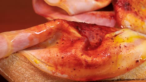 macro shot de aceite de oliva vertido en una rebanada sazonada de jamón encima de una rebanata de pan, macro shot en 4k
