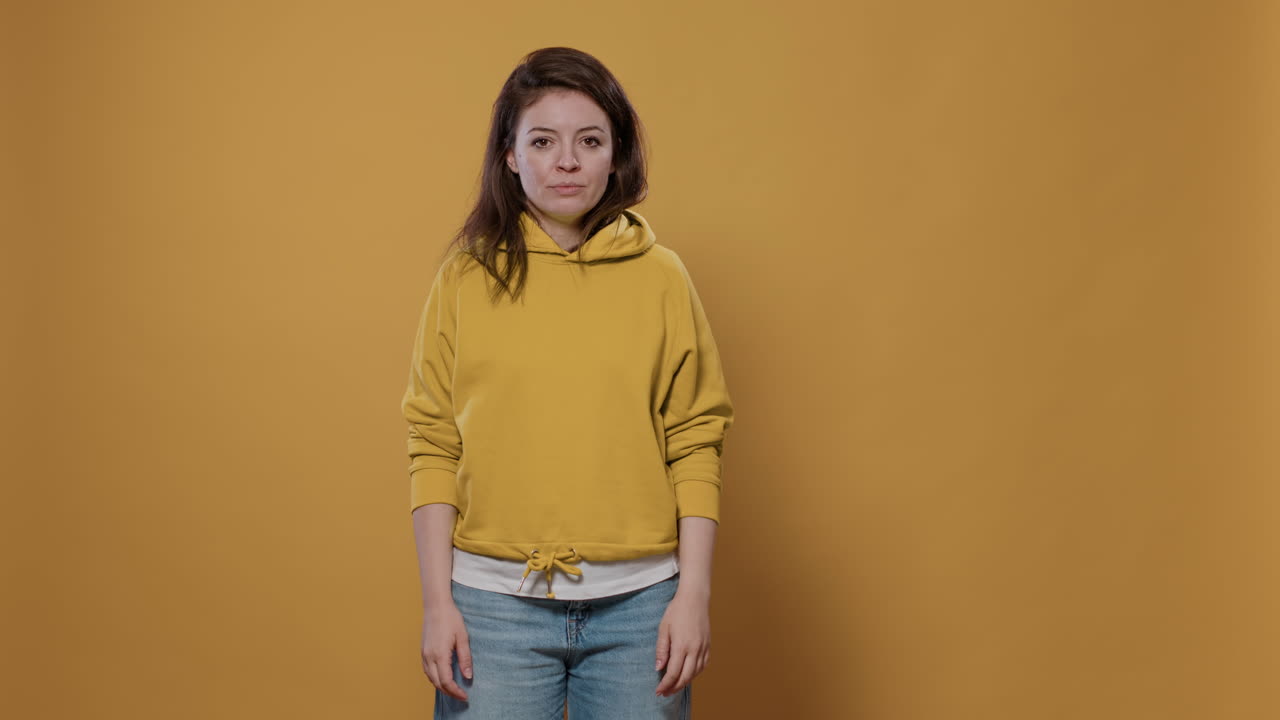 Woman in yellow hoodie expressing indifference