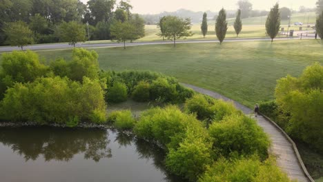 aerial footage of female jogger at a green park during sunrise