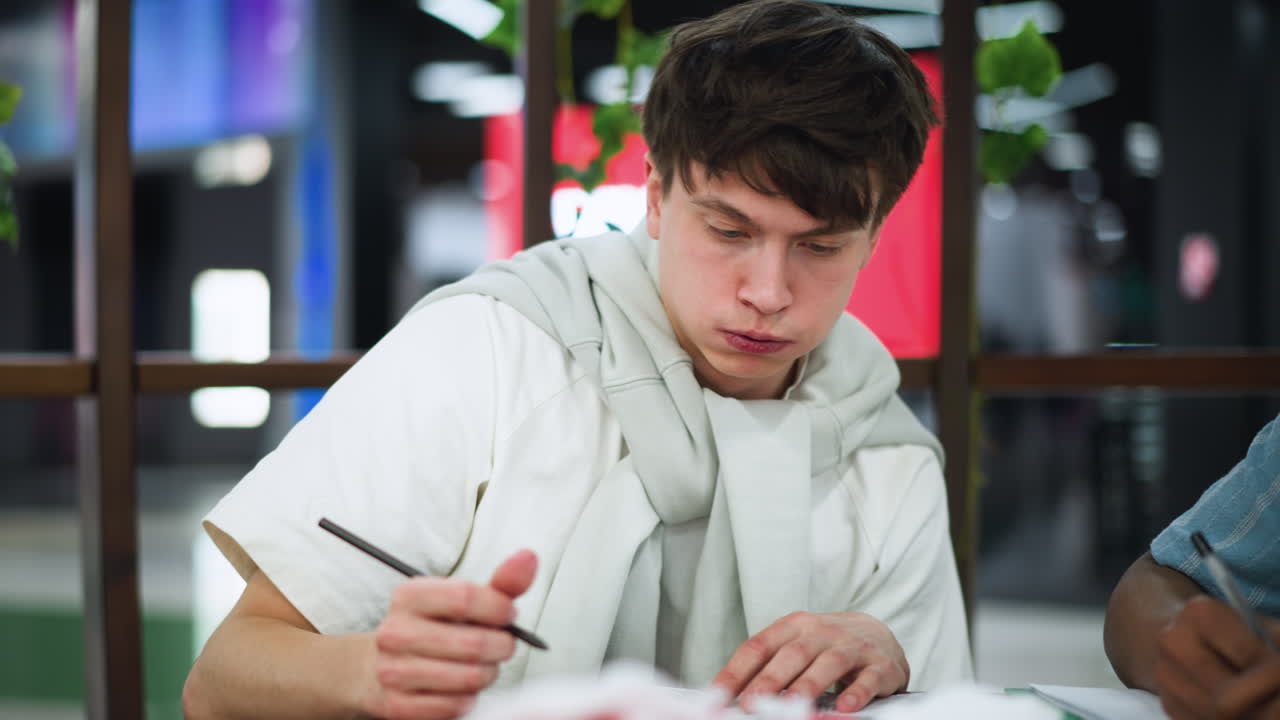 Busy white lad with puffed cheeks exhaling softly during focused drawing session capturing subtle breath motion and gentle rhythm creating calm creative atmosphere under warm indoor lighting