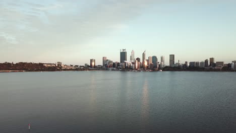 aerial, white drone flying in foreground, city skyline and water in background