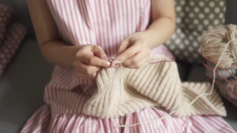 Close-up-female-knitting-hands.-Woman-hobby-knitting-wool-sitting-on-couch