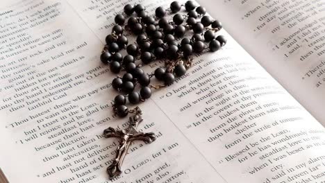 rosary beads placed on open bible close up panning shot