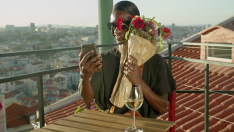 gay feliz teniendo una videollamada con su amante y mostrándole flores