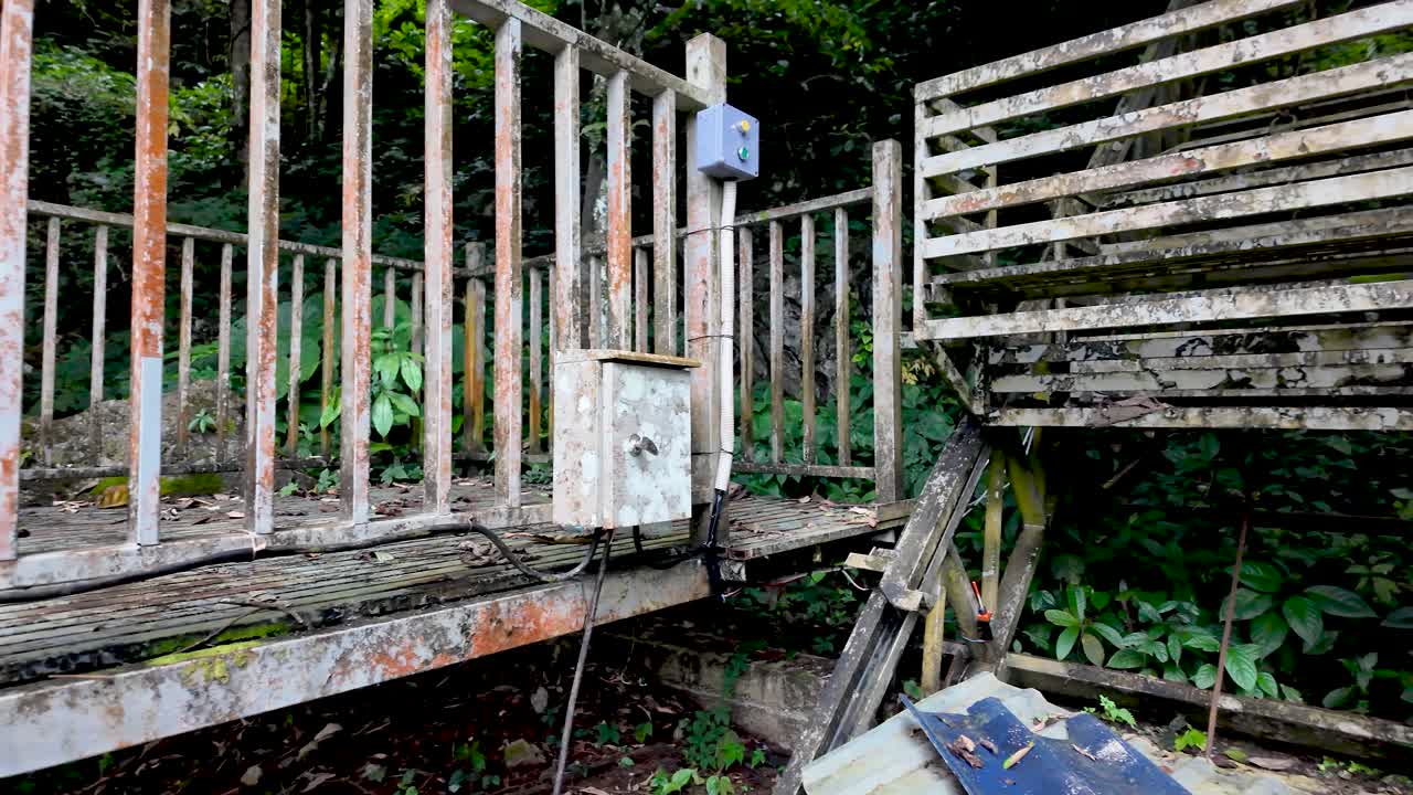 Dilapidated chair lift station with rusty electrical box showing neglect and decay over time
