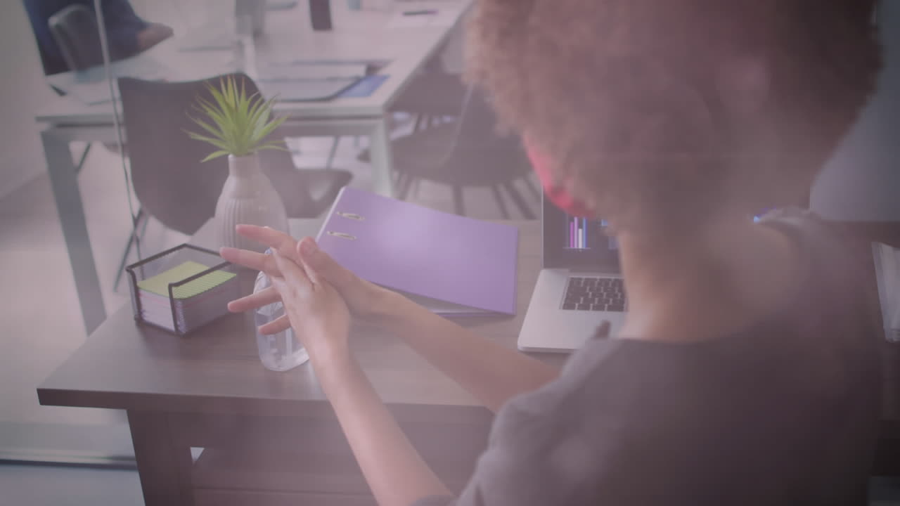 얼굴 마스크를 쓰고 사무실에서 손을 소독하는 여성 위에 반 ⁇ 이는 불빛의 애니메이션