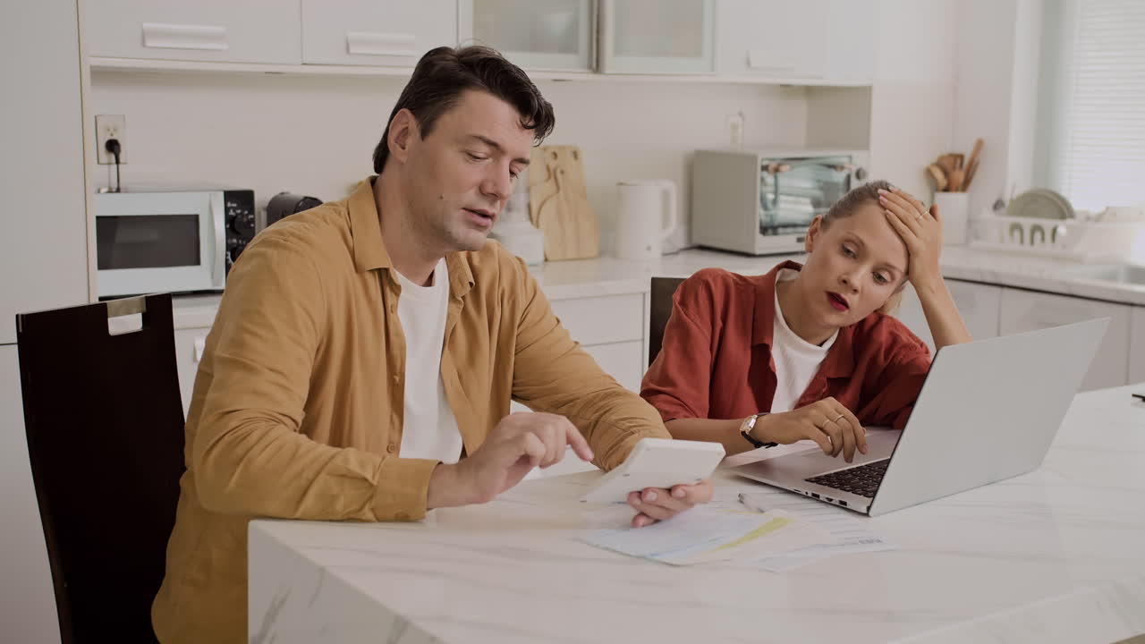 Coppia caucasica che discute del pagamento delle bollette usando il laptop a casa