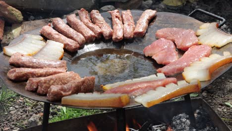 Traditional-Romanian-food-grilling-over-wood-fire-on-grilling-disc