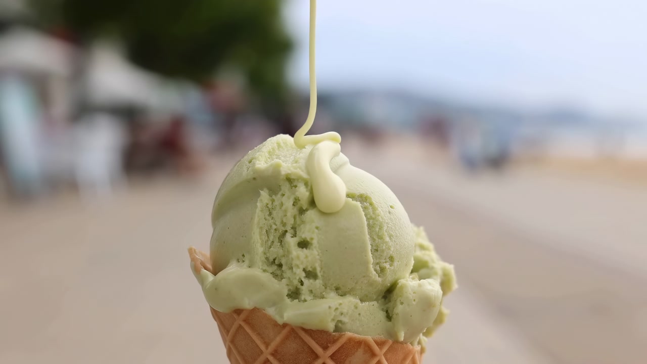 Cono gelato verde che cola salsa verde, in spiaggia con ombrelloni e sabbia, con gelato verde, cono waffle, scena da spiaggia, con gelato, materiale del cono waffle, texture della salsa, dettaglio nitido.