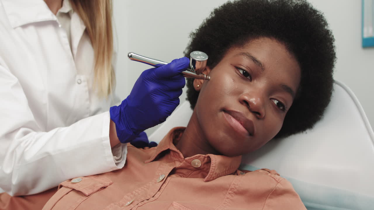 Estetista esegue una procedura cosmetica di dermoabrasione sul viso di una cliente in una clinica di bellezza con apposito macchinario