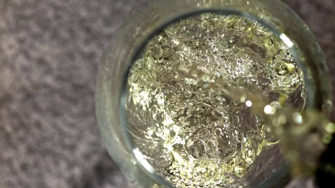 Versamento al rallentatore di liquido dorato in un bicchiere