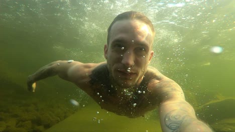 a young man films himself with an action camera as he swims through the dark, gloomy and murky the cold norwegian water during a hot summer day