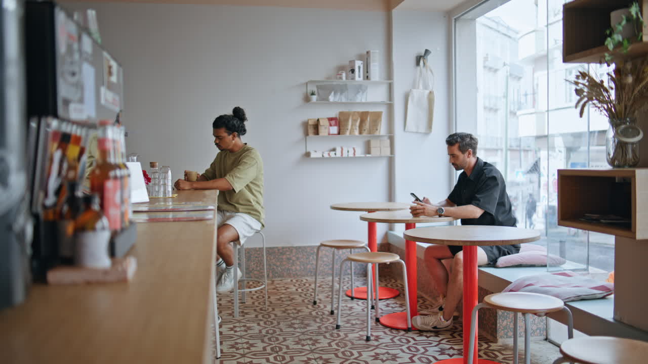 두 남자의 방문객이 테이블에 따로 앉아있는 아한 커피 하우스 인테리어.