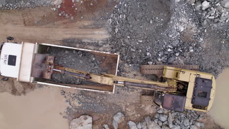 una toma dinámica de un avión no tripulado de una excavadora que vacía su rendimiento en un camión de minería