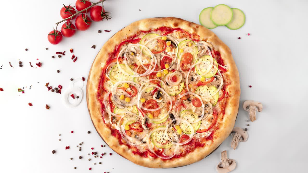 круглая свежая пицца с луком, перцем, овощами, помидорами, кукурузой, zucchini, грибами вращается на белом столе, вид сверху, копирование пространства. бесшовная циклическая анимация