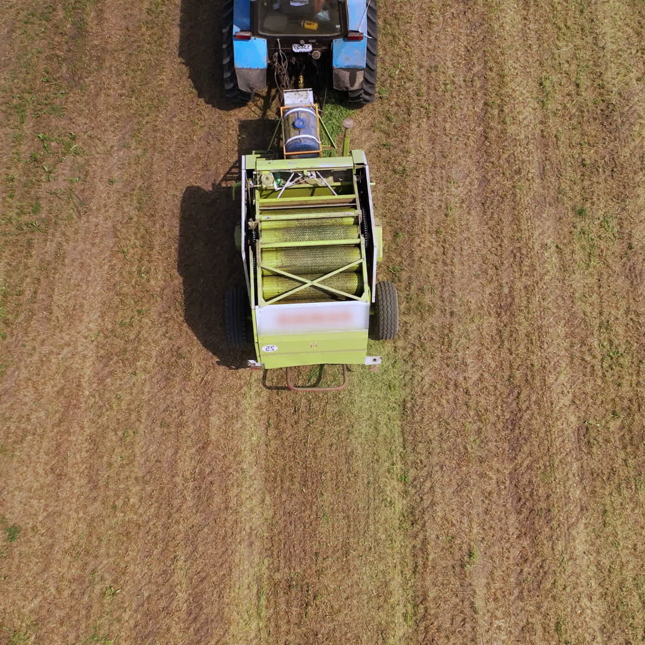 Working process of agricultural tractor outdoors in summer. Top view of special pressing machine on the field background.