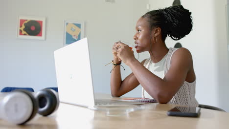 african american young woman with braided hair is using laptop, at home