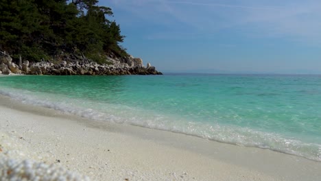 Cámara-Lenta-De-Olas-Salpicando-En-Una-Playa-De-Guijarros-Blancos-Con-Un-Cielo-Azul-Claro-En-El-Fondo,-Playa-De-Mármol,-Isla-De-Thassos,-Grecia