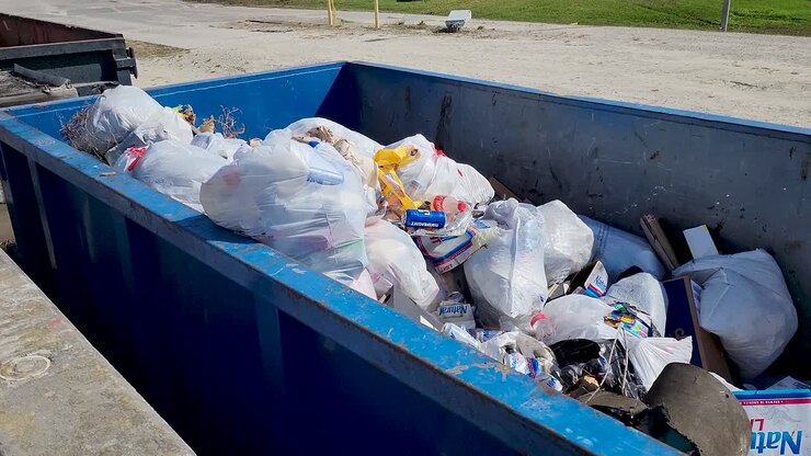 Drive up roll off dumpster filled with bagged trash and other debris