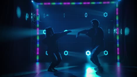 two dancers performing on stage with vibrant lighting effects