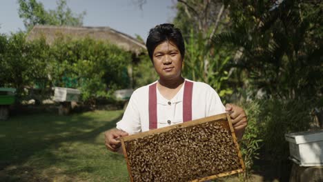 a beekeeper holding a frame of bees at an apiary