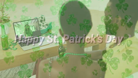 feliz día de st patricks texto y hojas de trébol contra pareja teniendo videollamada en portátil en casa